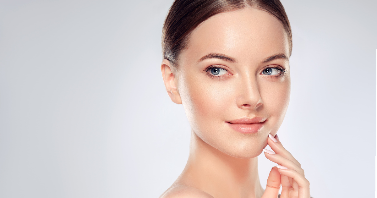Woman with clear glowing skin touching her face, representing the results of ZO Skin Health in Pocatello, ID